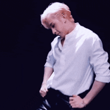 a man in a white shirt is dancing on a stage in front of a black background .