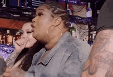 two women are sitting in a bar talking to each other . one of the women is wearing hoop earrings .