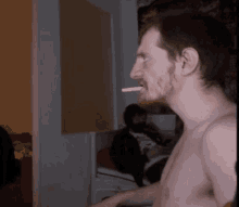 a shirtless man is smoking a cigarette in a dark room