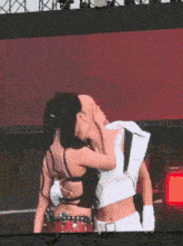 a couple of women are hugging each other on a stage in front of a large screen .