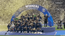 a group of soccer players are standing under a banner that says " winners "