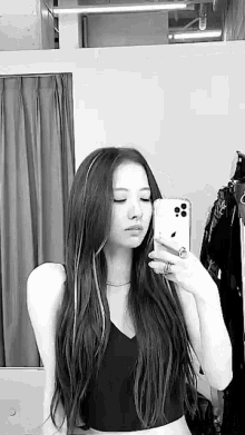 a black and white photo of a woman taking a selfie in a mirror .