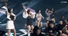 a group of women are dancing on a stage in front of a livex sign