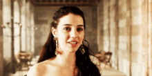 a woman in a dress and earrings is smiling in a room .