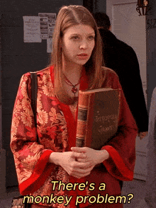 a woman in a red robe holding a book that says " there 's a monkey problem "