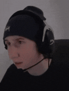 a man wearing headphones and a beanie is making a face .