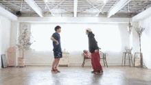 two young men are dancing in a room with a chair in the background .