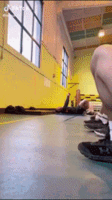 a person laying on the floor in a gym with a yellow wall behind them