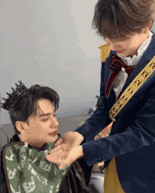 a man with a crown on his head is being touched by another man in a suit