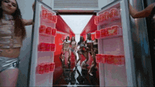 a group of women are standing in front of a refrigerator filled with soda