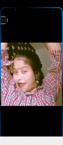 a woman in a plaid shirt is dancing with her hands in the air