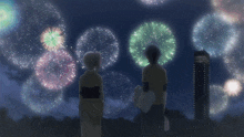 a man and a woman are looking at fireworks in the night sky