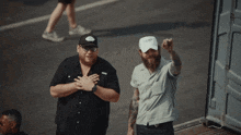two men are standing next to each other and one has a white hat that says ' i love you ' on it