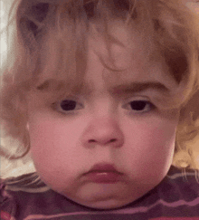 a close up of a baby 's face with a sad look on her face