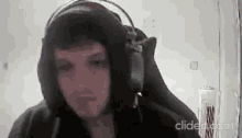 a man wearing headphones and a hoodie is sitting in front of a computer screen .