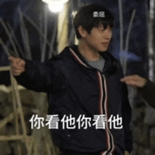 a man with chinese writing on his jacket is pointing at someone