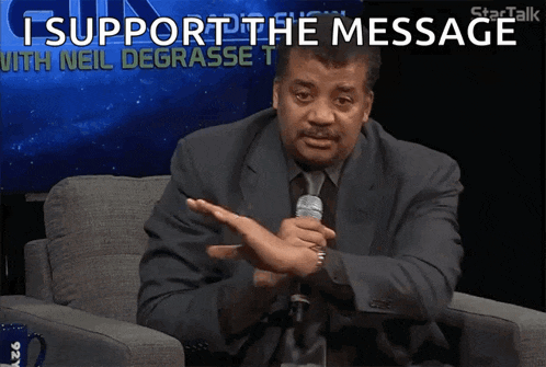 a man in a suit and tie holds a microphone and says i support the message with neil degrasse t.
