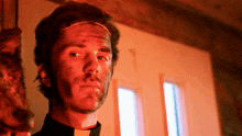 a man with red paint on his face and a black collar