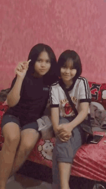 two girls are posing for a picture while sitting on a bed