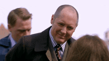 a man in a suit and tie is smiling and looking at the camera