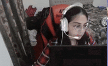 a woman wearing headphones and glasses is sitting in front of a computer monitor .