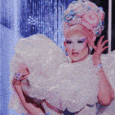a woman wearing a white dress and a pink and blue wig