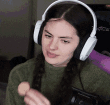 a woman wearing headphones and a green sweater is eating a cookie
