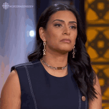 a woman wearing a dior necklace and earrings looks serious