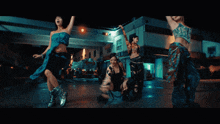 a group of women are dancing in front of a building that says ' a ' on it
