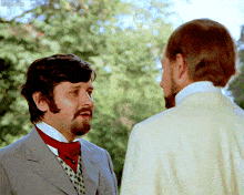 a man with a beard is talking to another man with a white shirt