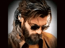 a man with long hair and a beard wearing sunglasses looks down