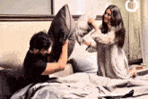 a man and a woman are pillow fighting on a bed
