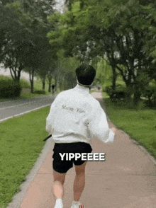 a man wearing a martin kim shirt is running on a path