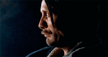 a close up of a man 's face with a beard in the dark