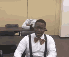 a man wearing a bow tie and suspenders is sitting at a table