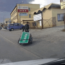 a man pushing a cart with a green sign that says reszow on it