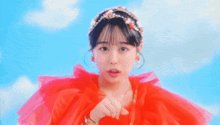 a woman wearing a red dress and a tiara is making a gesture