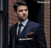 a man in a suit has a patch on his pocket that says rouxka