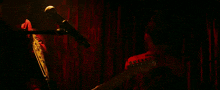 a woman holding a fender guitar in front of a red curtain