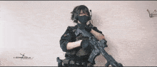 a person holding a rifle with a website written on the bottom of the image