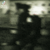 a blurry picture of a man in a black hat with tiktok written on the bottom