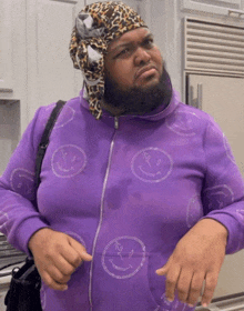 a man wearing a purple hoodie with smiley faces on it