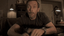 a man sitting on a couch wearing a black shirt that says nico on it