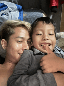 a young boy giving a thumbs up while being held by a man