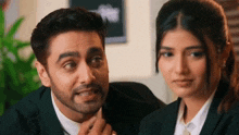 a man and a woman are sitting next to each other in a room . the man is touching the woman 's face .