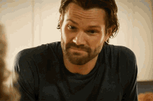 a man with a beard wearing a blue shirt looks at the camera