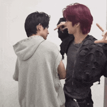 a man with red hair stands next to another man with black hair