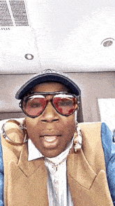 a woman wearing sunglasses and a hat is making a funny face while sitting in a chair .