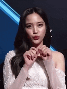 a woman is making a heart shape with her hands .