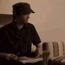 a man in a hat sits in a chair with a book